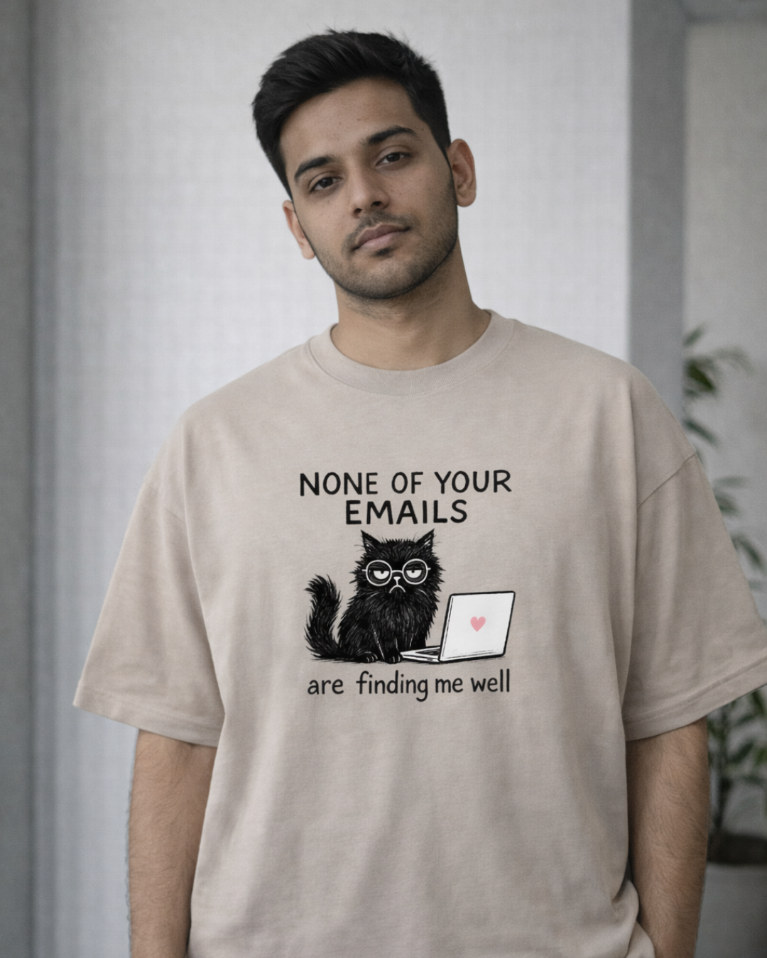 Man wearing a None of Your Emails Are Finding Me Well oversized t-shirt in a modern office